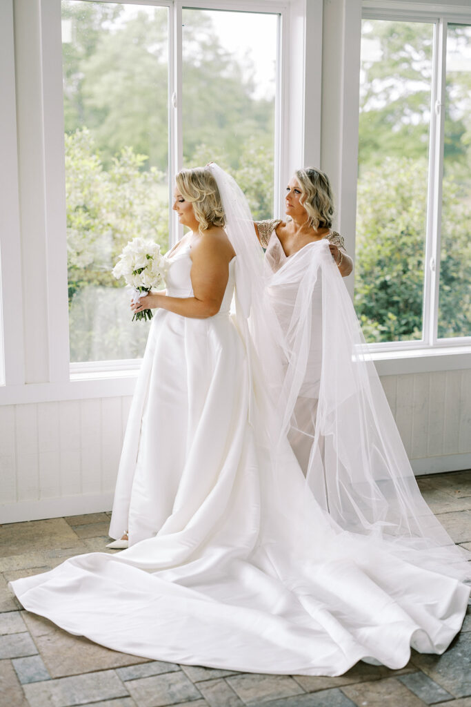 Bride and Mother of the Bride in the covered and enclosed patio at a wedding venue with vineyard located near Atlanta