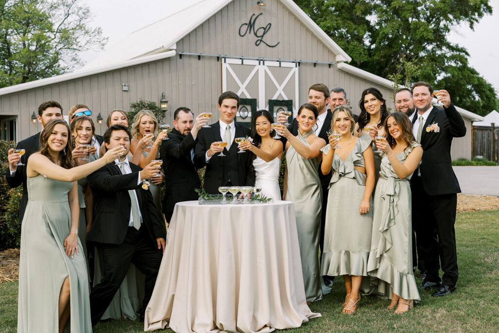 Champagne toast with the bride and groom and their bridal party in front of the modern barn at a wedding venue located in Newnan, GA