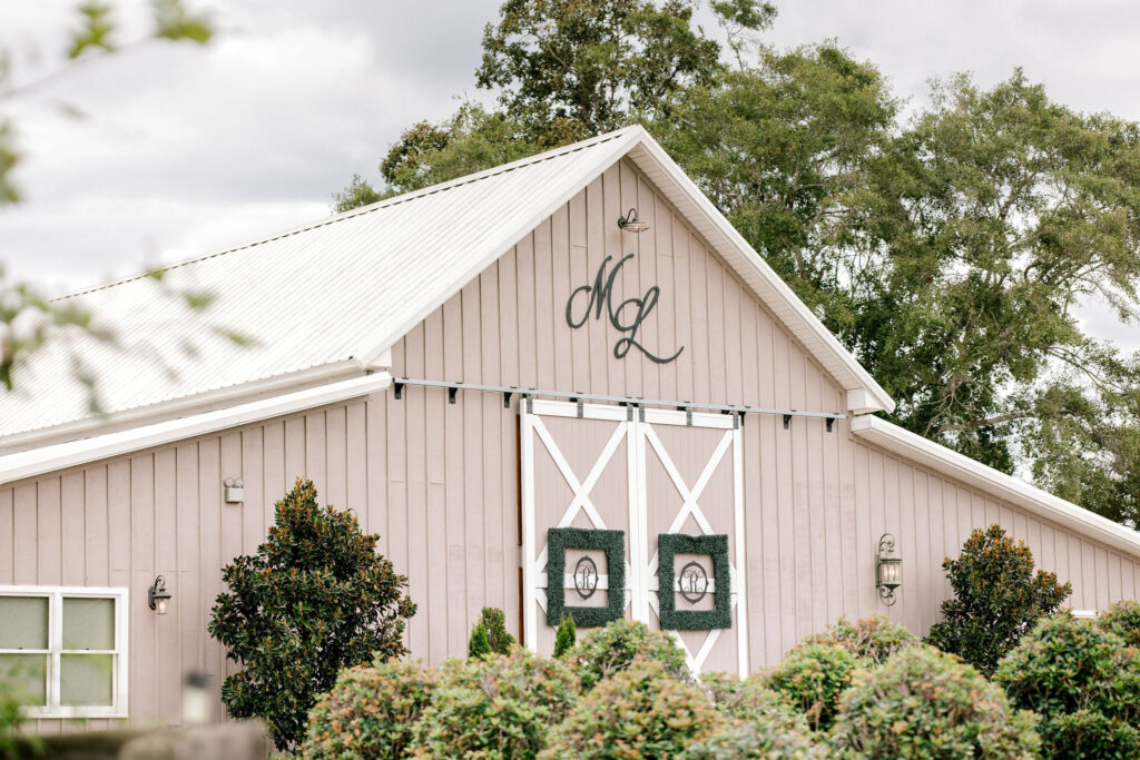 Our beautiful board and batten wooden barn with scripted letters and 16 ft sliding barn doors decorated with large square boxwood frames and personalized black metal letters for our couples celebrating their wedding at The Venue at Murphy Lane located one hour away from Atlanta, GA 