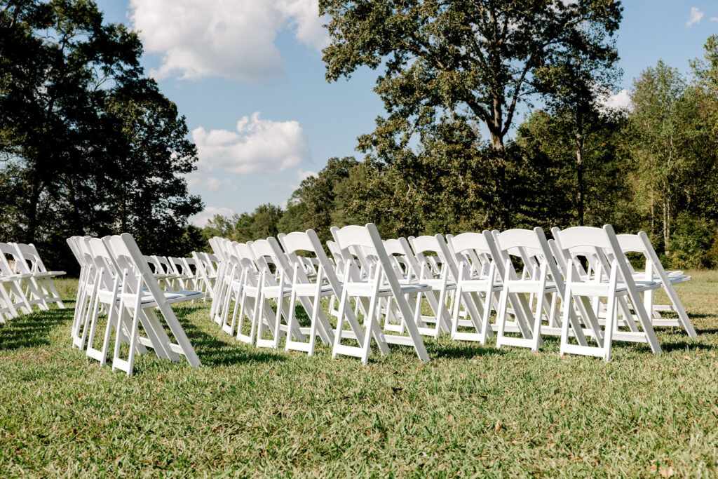 White padded resin chairs are all set up for an outdoor wedding ceremony at the Big Oak Tree site located in Newnan, GA at The Venue at Murphy Lane  