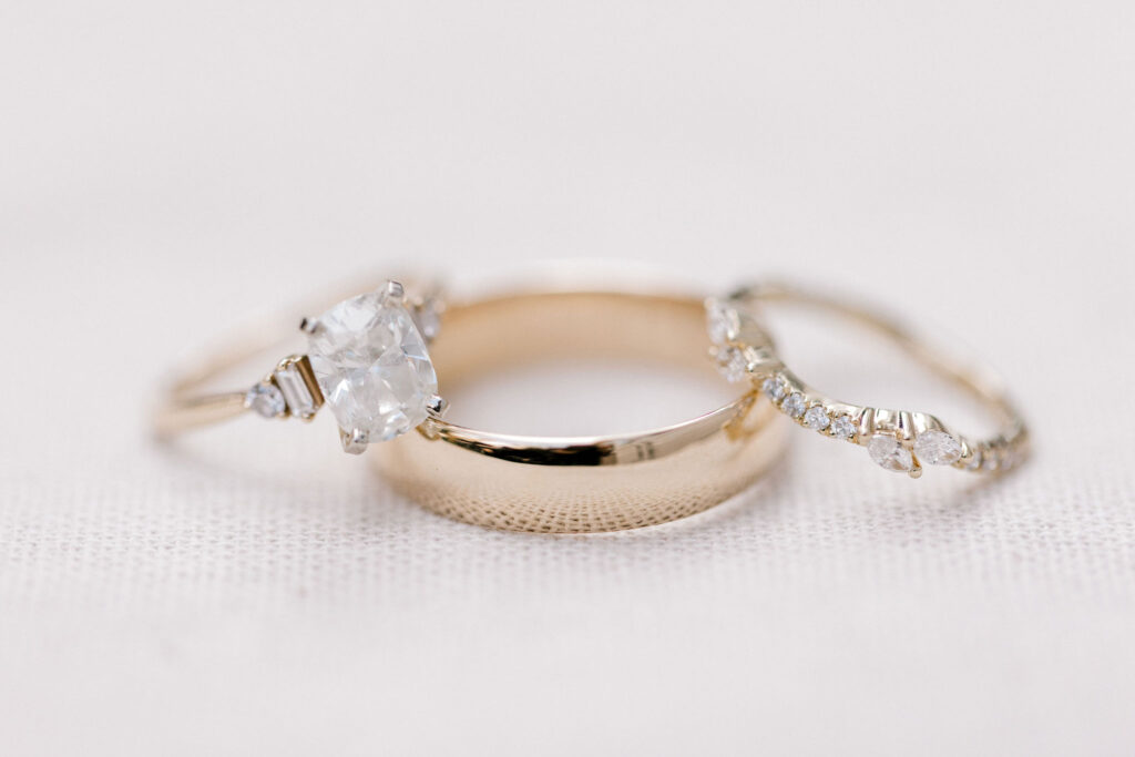 The bride's rings are made of gold bands with shiny white diamonds.  The groom's wedding band is gold and shiny.  They will exchange rings during the wedding ceremony.