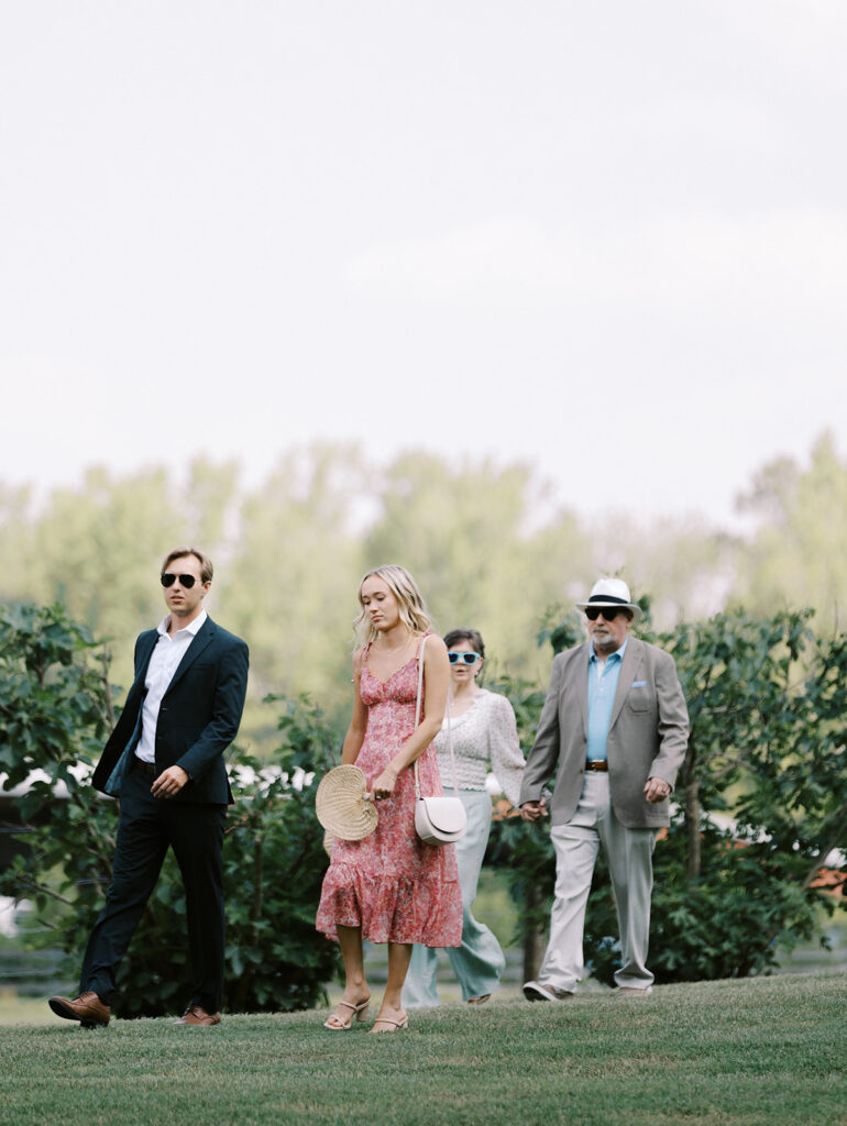 Wedding guests walk down the gentle rolling hillside towards the wedding site located in the valley at The Venue at Murphy Lane in Newnan, GA just one hour away from Atlanta, GA 