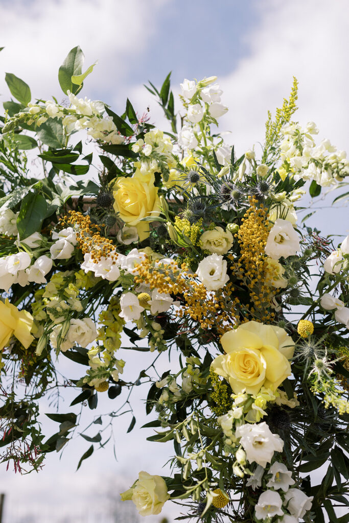 Grand floral installation on an arbor at a wedding ceremony with yellow blooms. 