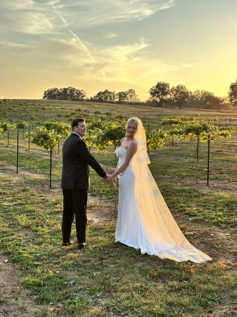 A bride and groom walk in a vineyard at a wedding venue near Atlanta. The sunset gives the golden hour effect for photography.